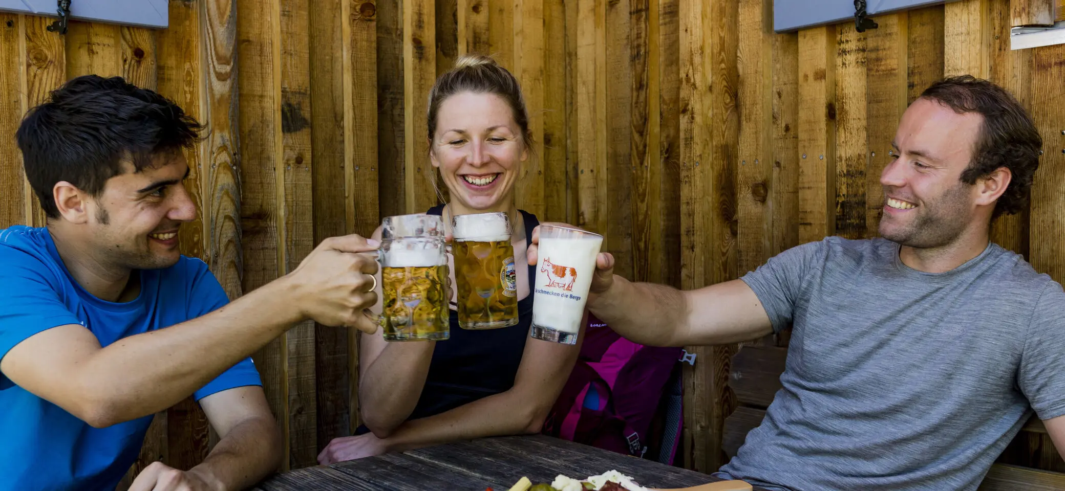 Auf der Hütte: Drei Personen stoßen mit Bierkrügen an | © DAV/Hans Herbig